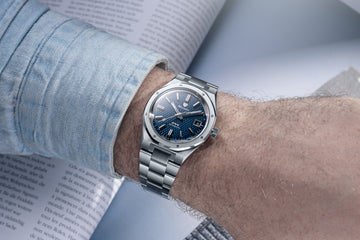 Nivada Grenchen F77 Blue MK2 38mm automatic watch worn on wrist with integrated stainless steel bracelet and tressed blue dial over open book