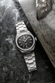 Nivada Grenchen F77 MKII Meteorite 38mm on flat link bracelet displayed beside raw meteorite stone