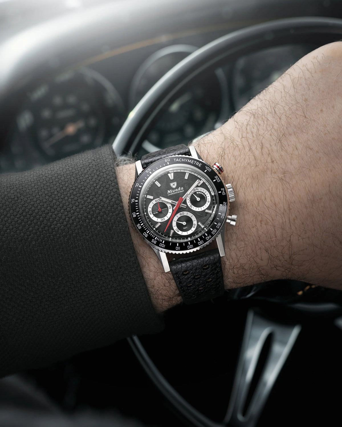 Nivada Grenchen Chronoking Mecaquartz Racing Black worn on wrist in front of a classic car steering wheel