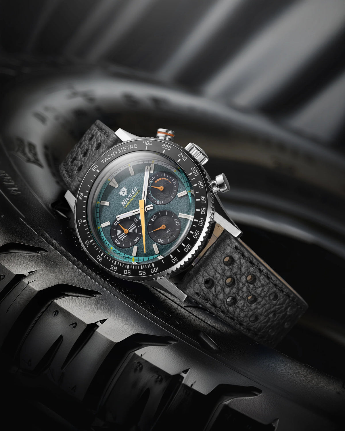 Nivada Grenchen Chronoking Mecaquartz Racing Green resting on a black tyre with perforated leather strap