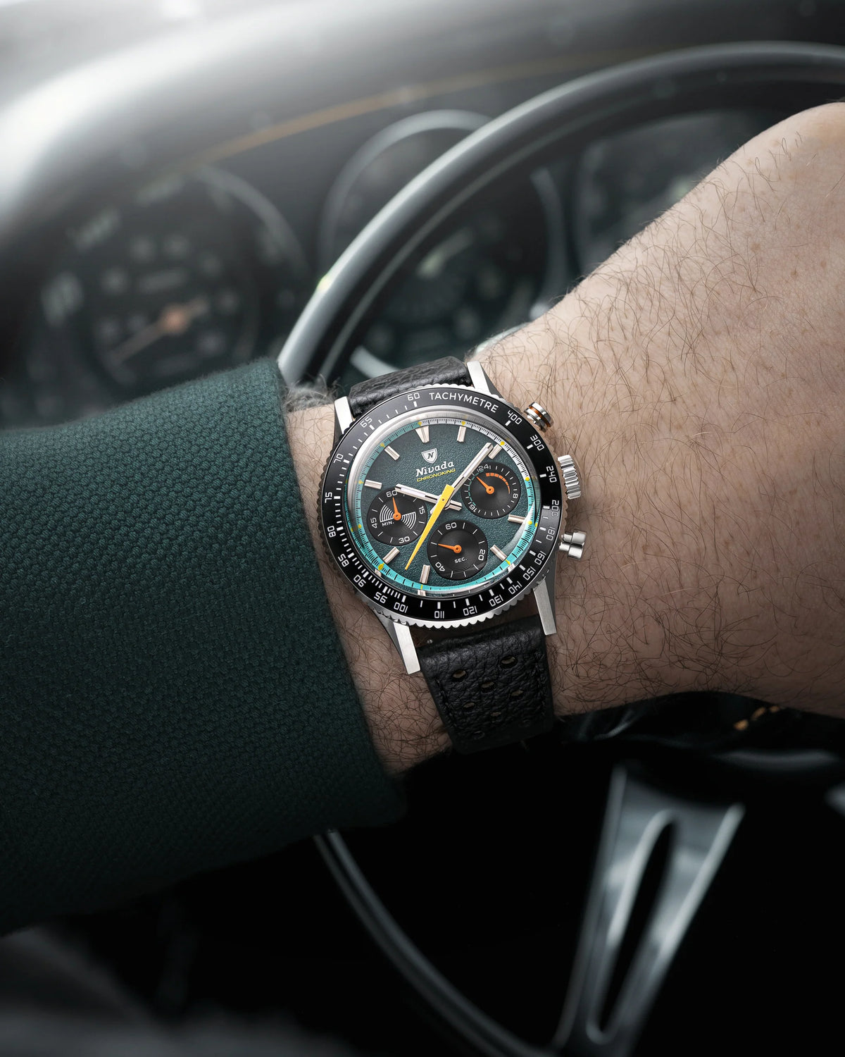 Nivada Grenchen Chronoking Mecaquartz Racing Green worn on a wrist beside a car steering wheel