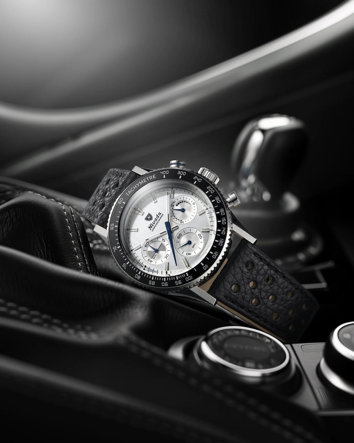 Nivada Grenchen Chronoking Mecaquartz Racing Grey with white dial resting on black leather car interior