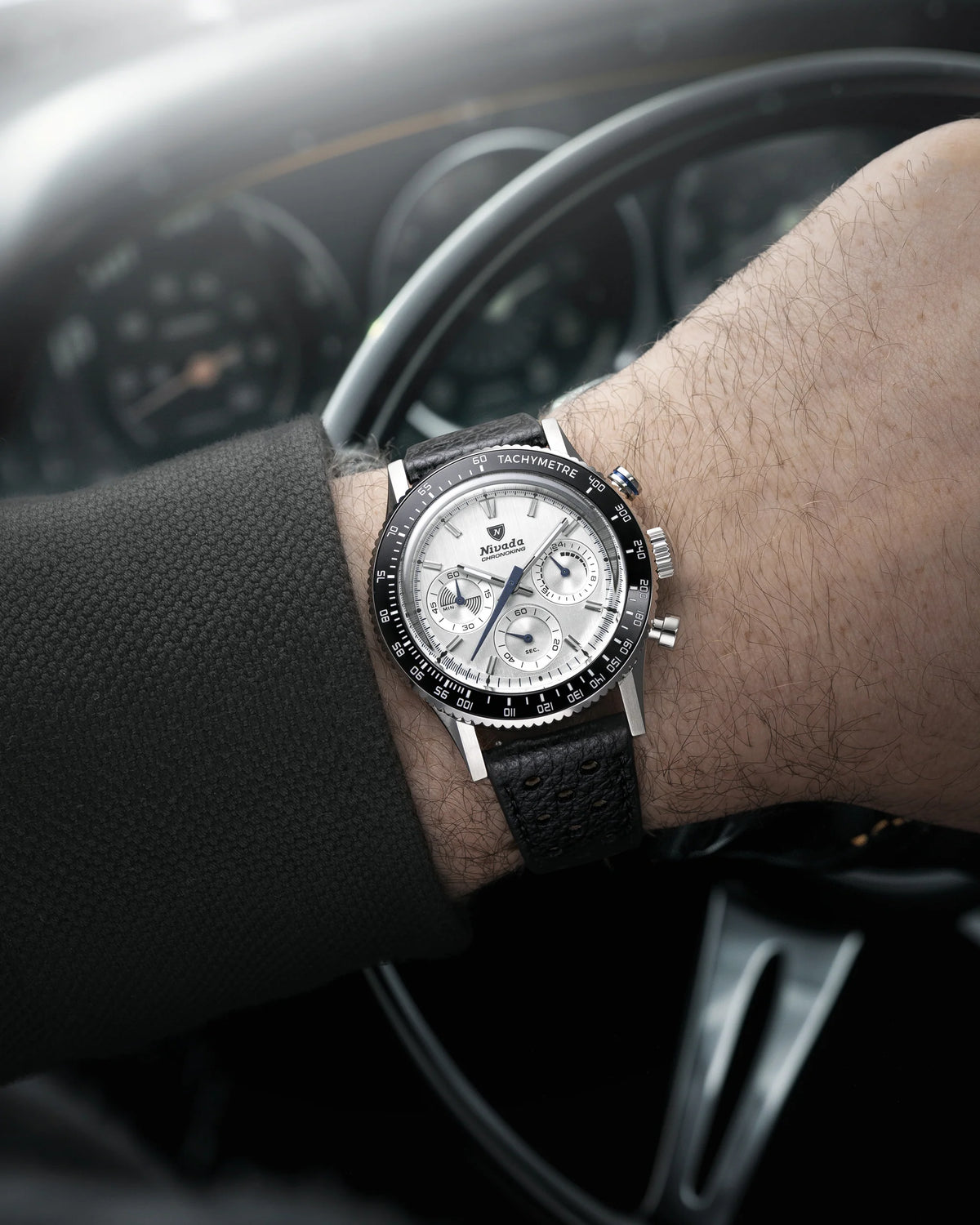 Nivada Grenchen Chronoking Mecaquartz Racing Grey with white dial worn on a wrist at a steering wheel